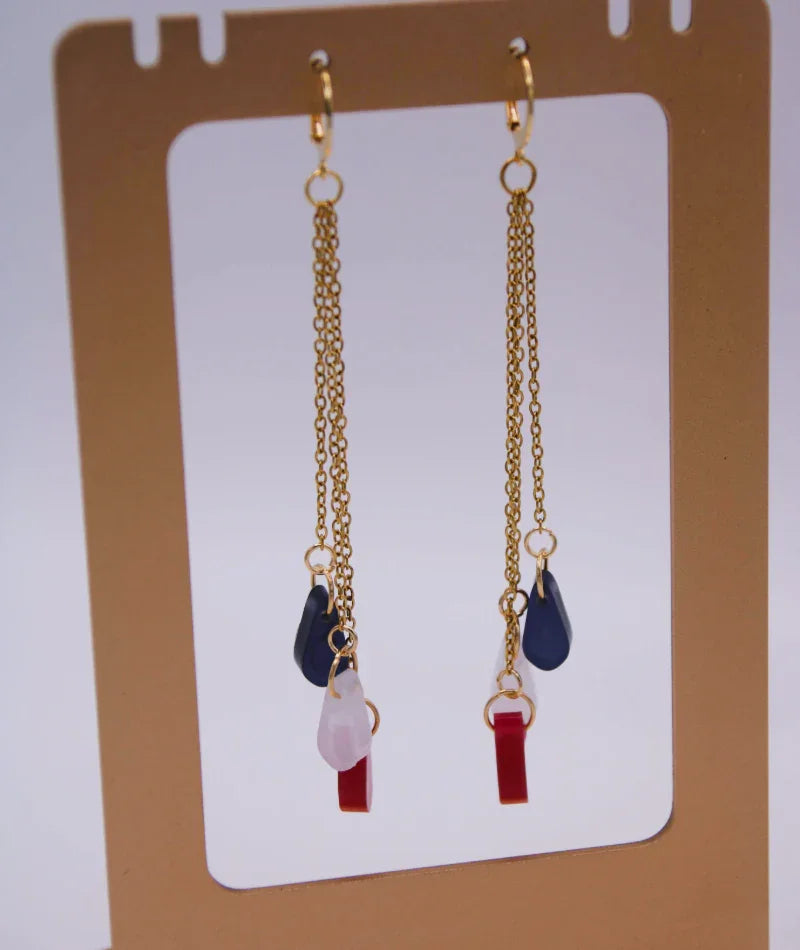 Pendientes largos artesanales con cadenas doradas y piedras en tonos rojo y azul, inspiración colombiana