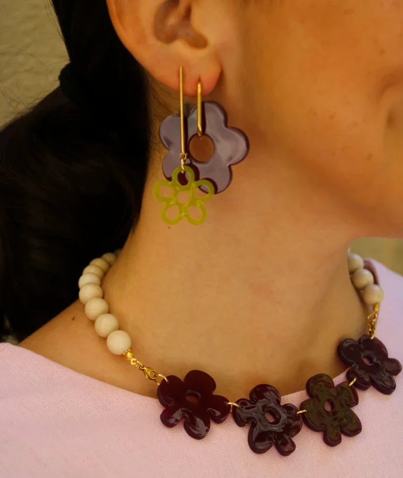 Pendientes y collar artesanales con flores en tonos morados y verdes, inspirados en la cultura colombiana
