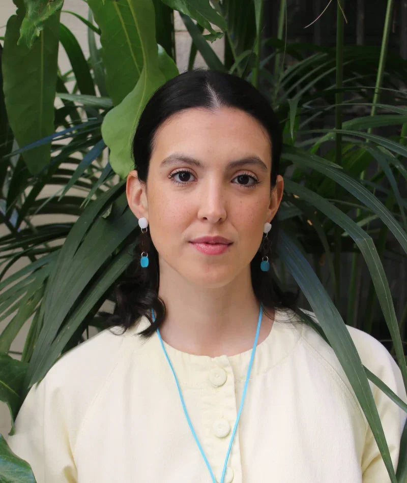 Mujer con aretes artesanales azules y collar de cuerda, joyería inspirada en cultura colombiana