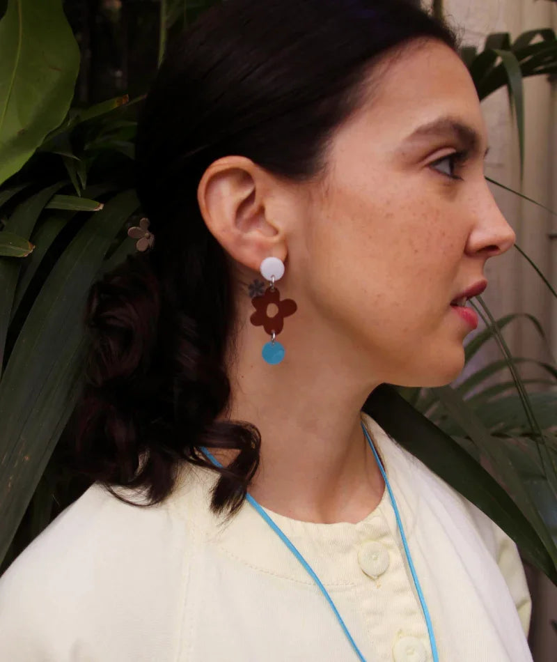 Pendientes artesanales con flor marrón y círculo azul, joyería inspirada en cultura colombiana