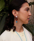 Pendientes artesanales con flor marrón y círculo azul, joyería inspirada en cultura colombiana