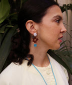 Pendientes artesanales con flor marrón y círculo azul, joyería inspirada en cultura colombiana