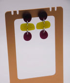 Pendientes artesanales con formas geométricas en amarillo y morado, inspirados en la cultura colombiana
